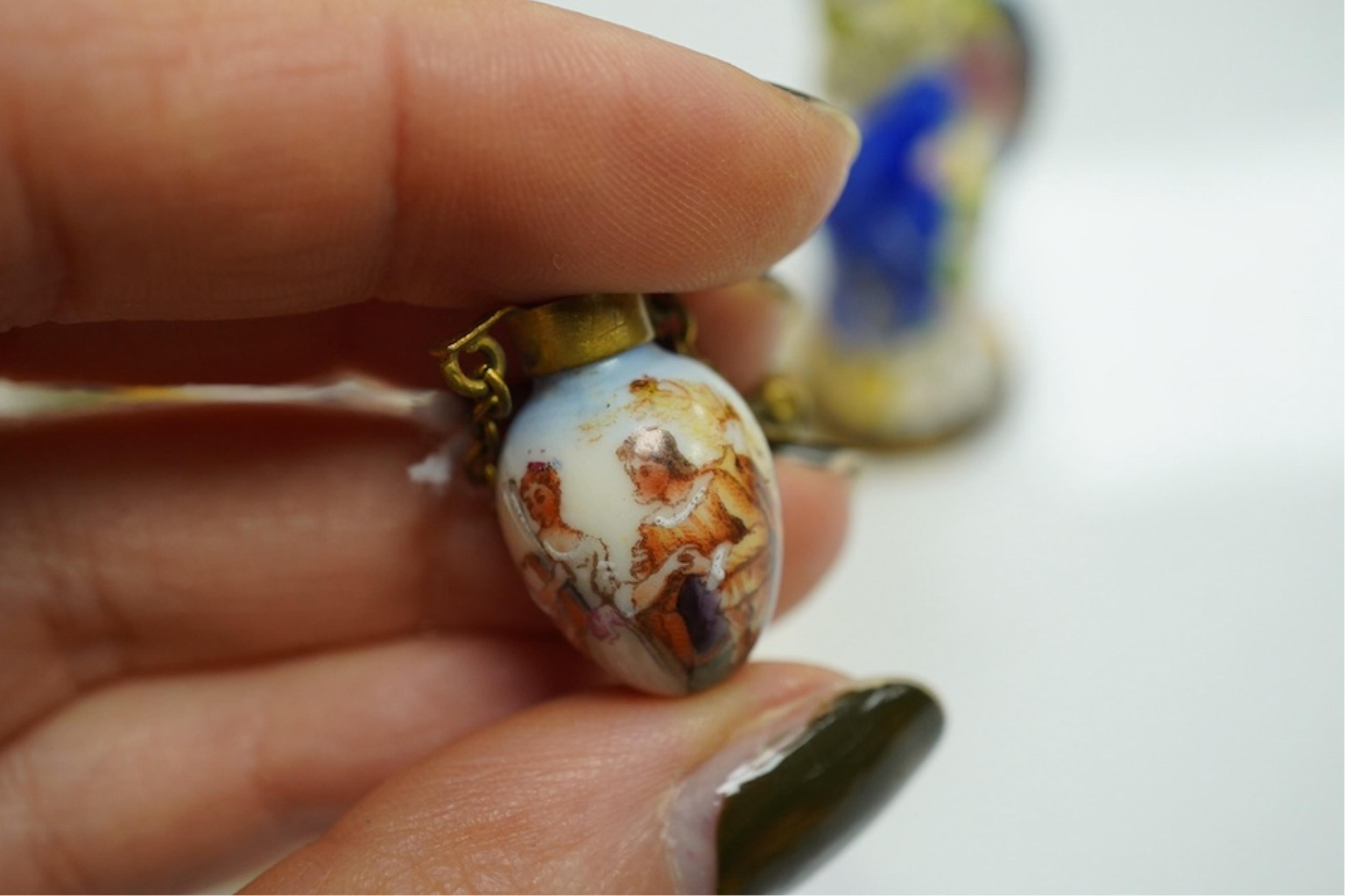 A miniature porcelain egg shaped scent bottle, on chain, two Halcyon Days scent bottles and a circular enamelled paperweight, (4). Condition - fair